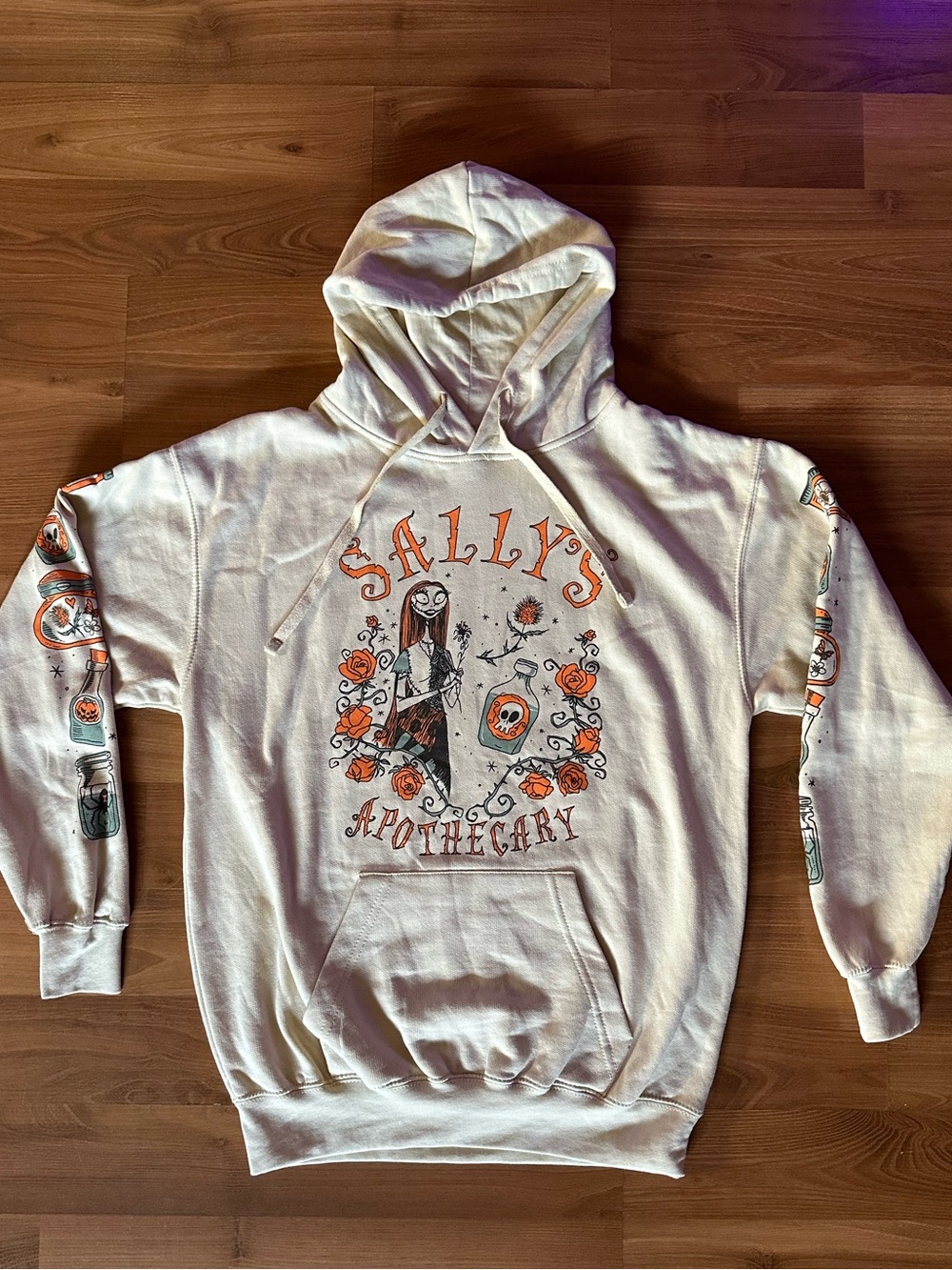 🆕 Disney Sally's Apothecary Cream Hoodie with Orange & Black Graphics